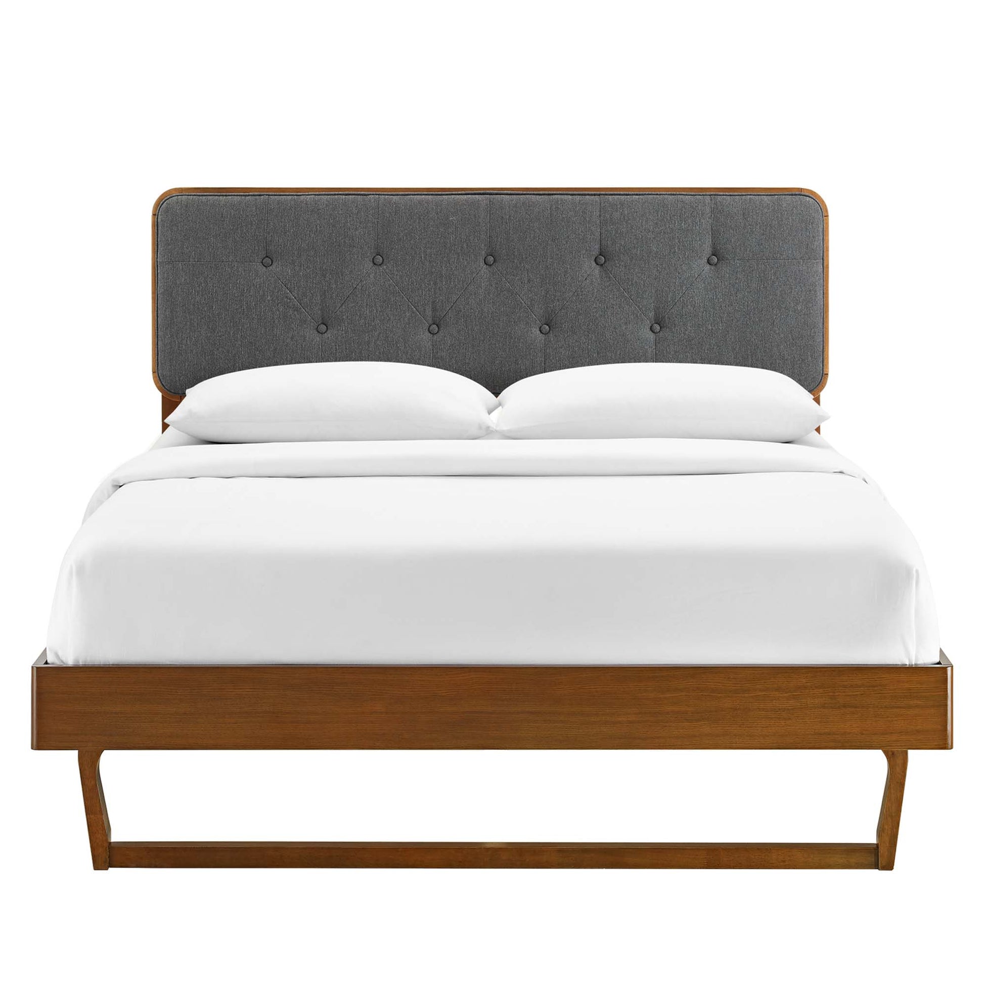 Walnut wood platform bed with charcoal tufted fabric headboard and white bedding, mid-century modern style.