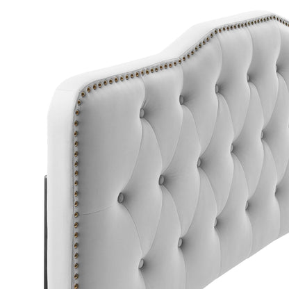 Light gray tufted fabric headboard with button tufts and brass nailhead trim along the edge.