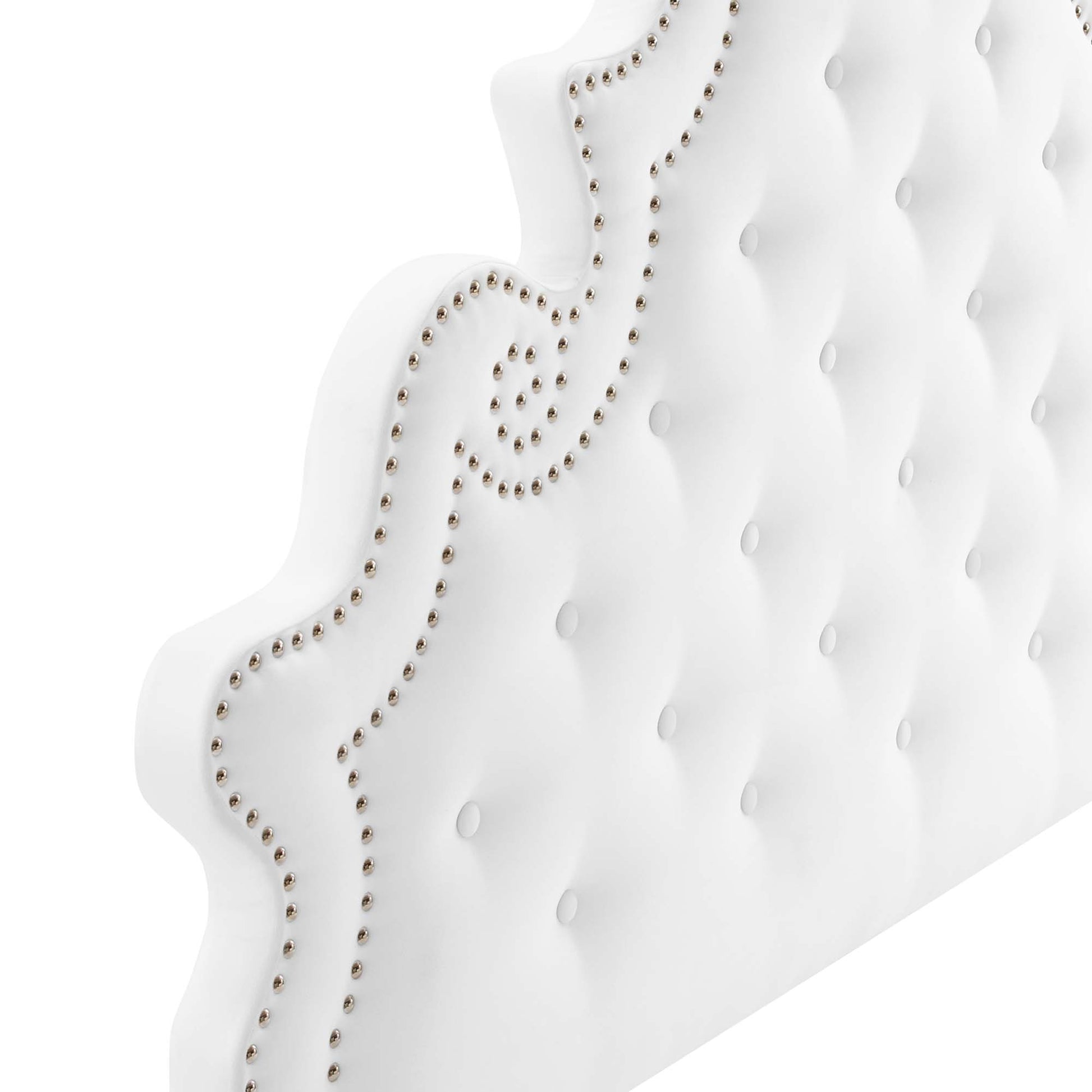 White tufted upholstered headboard with silver nailhead trim and scrolling border.
