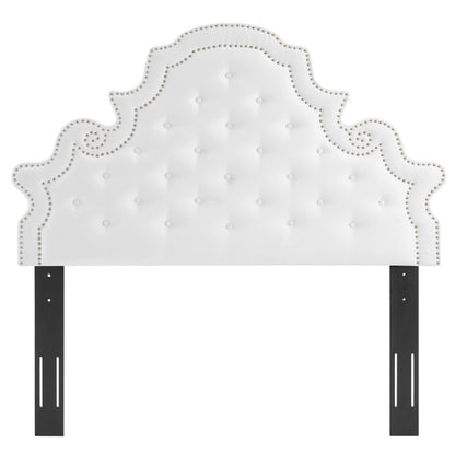 White tufted headboard with ornate curved silhouette and nailhead trim, mounted to black metal posts.