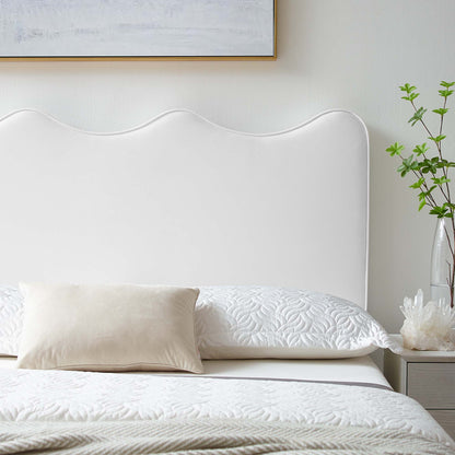 White scalloped upholstered twin headboard with quilted white bedding and beige lumbar pillow in a serene bedroom