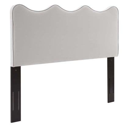 Light gray upholstered headboard with a wavy top and dark wood legs for a modern bed.