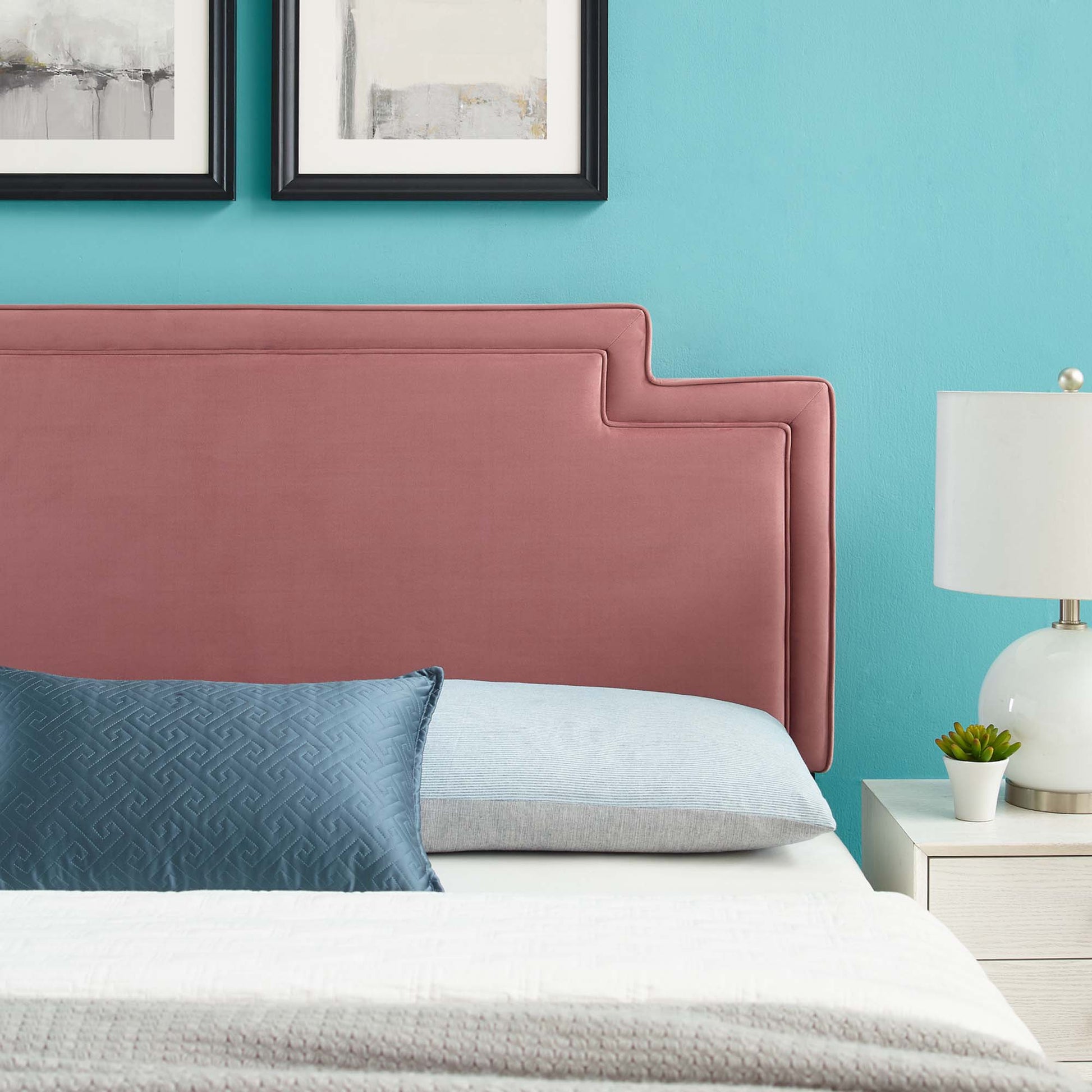 Dusty rose velvet twin headboard with stepped edge on teal wall, blue lumbar pillow, light blue pillow, white bedding, nightstand lamp.