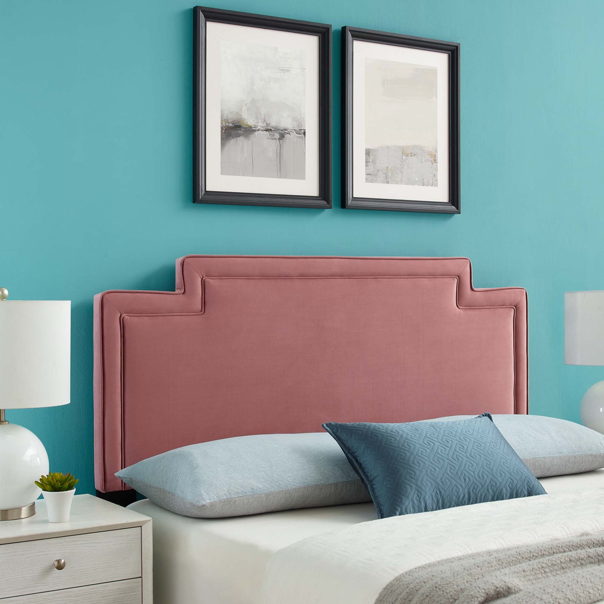 Blush pink velvet upholstered bed headboard with stepped silhouette, teal wall backdrop, abstract framed art.