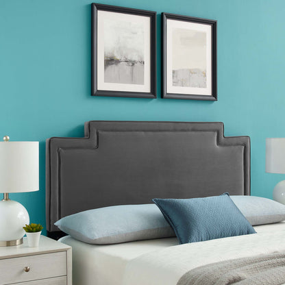 Grey upholstered headboard with stepped edges on teal wall; two framed abstract prints, light blue bedding, white nightstands.