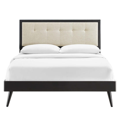 Brown wood king platform bed with splayed legs, beige tufted headboard, and white bedding.