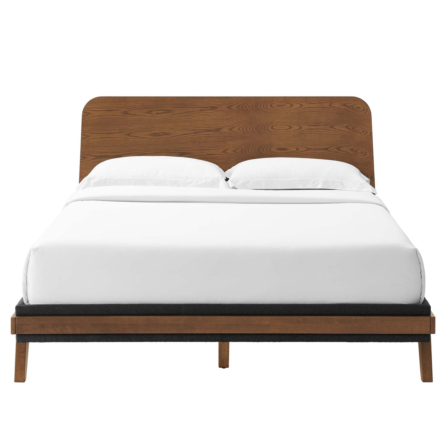 Walnut wood platform bed with rounded headboard, white linens, black base trim & mid-century legs.