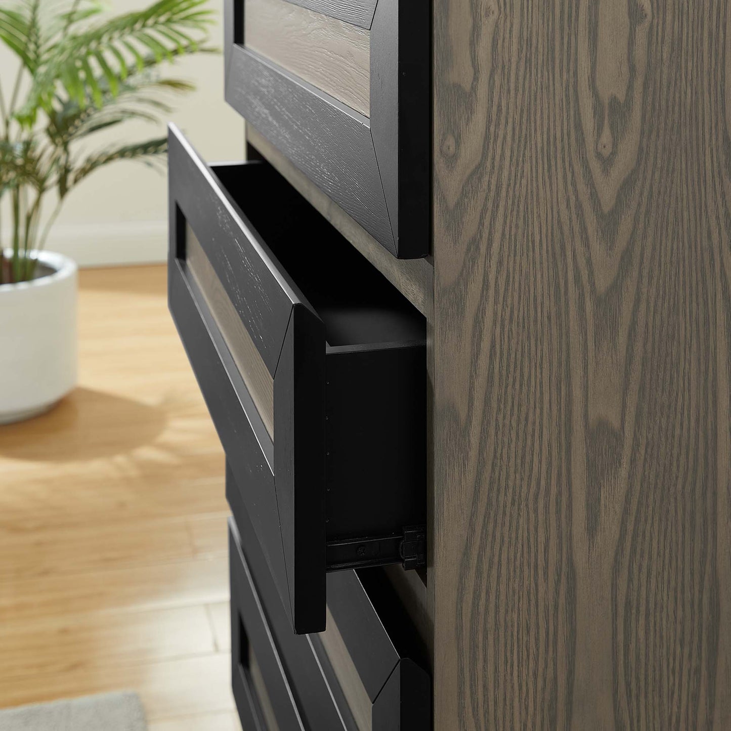 Tall oak-textured chest with gray drawer fronts; open drawer reveals black interior.