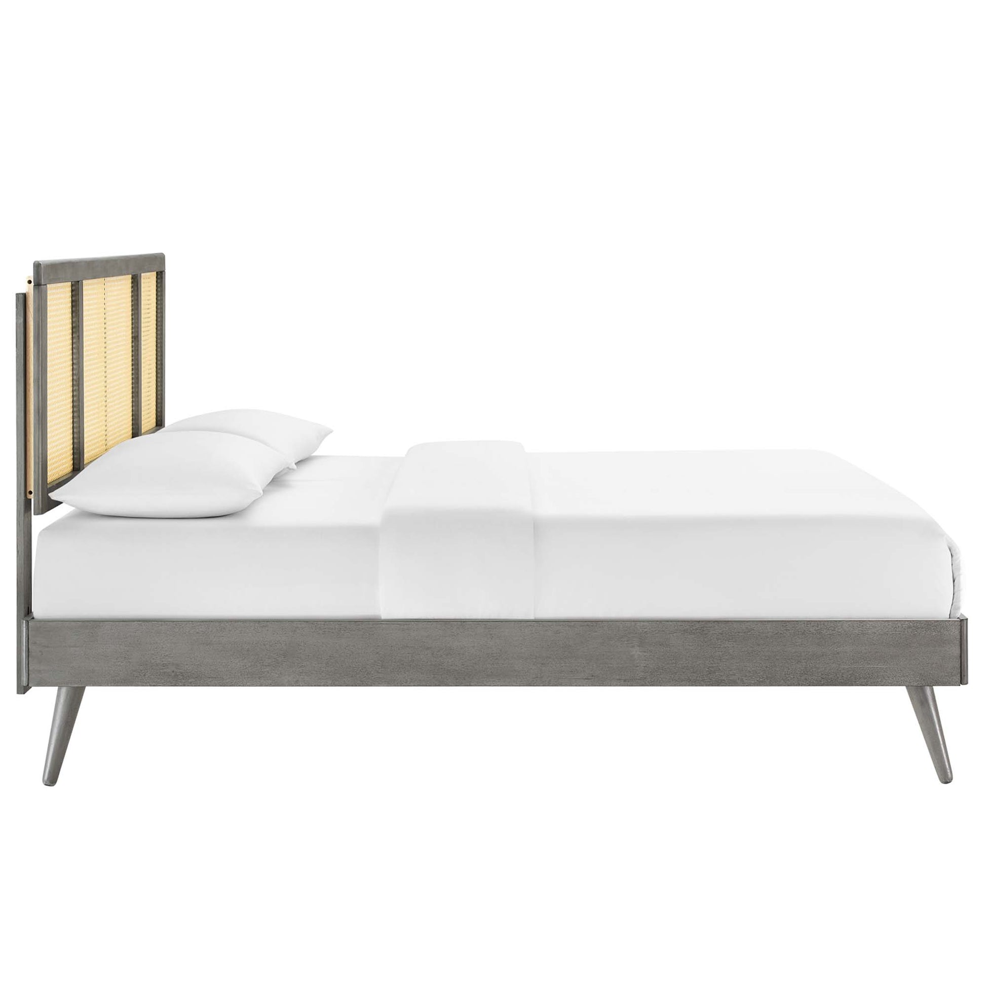 Gray wood platform bed with a woven cane headboard, white bedding, mid-century modern style with splayed legs.