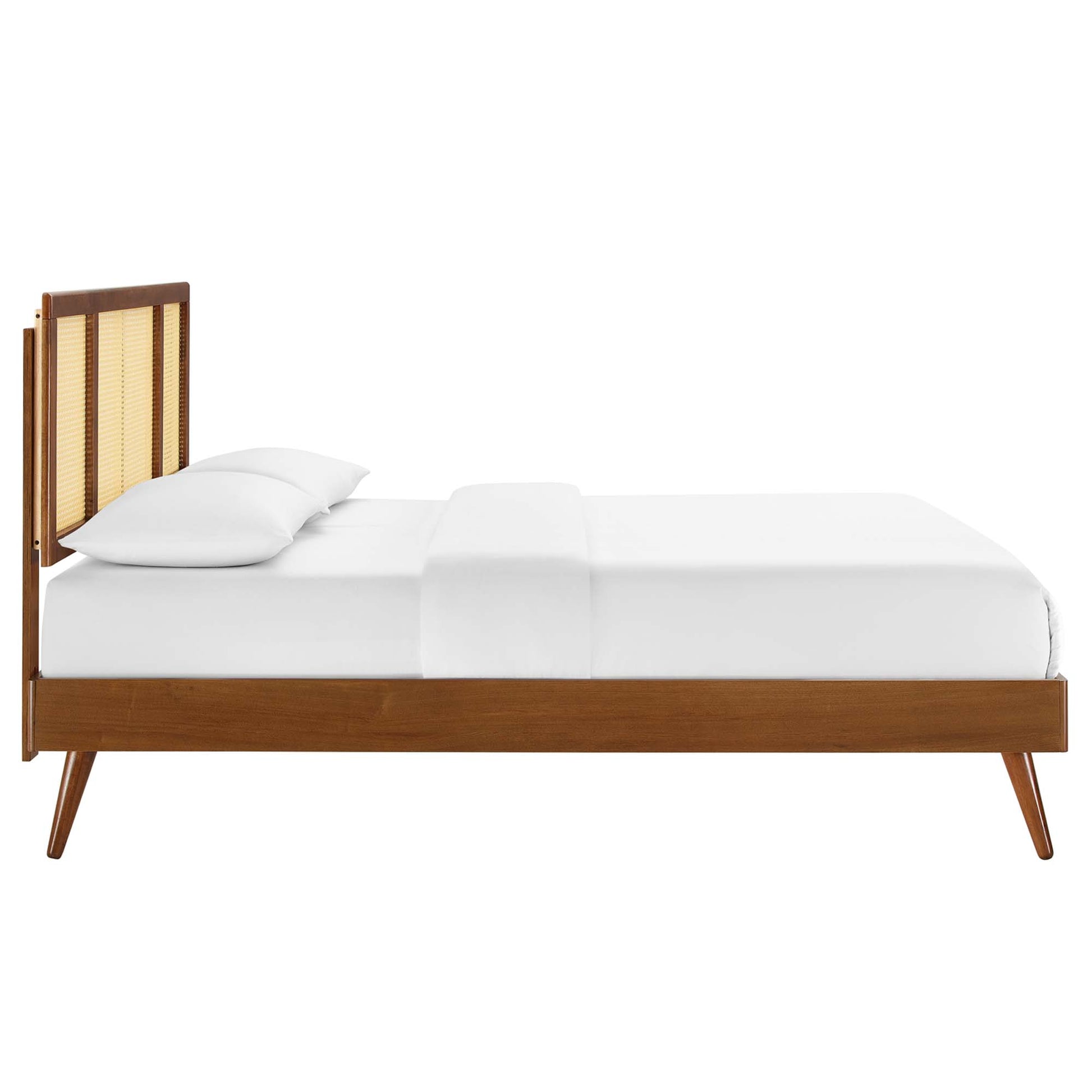 Walnut mid-century platform bed with cane-back headboard, tapered legs, and white linens.