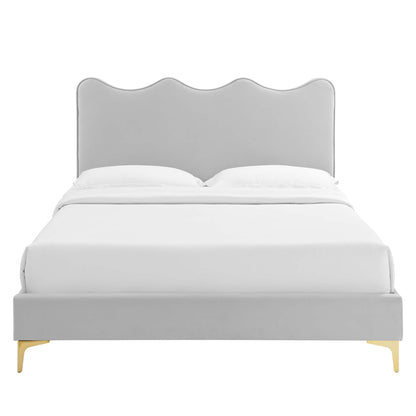 Light gray upholstered bed with a scalloped wave headboard, white bedding, and gold legs.