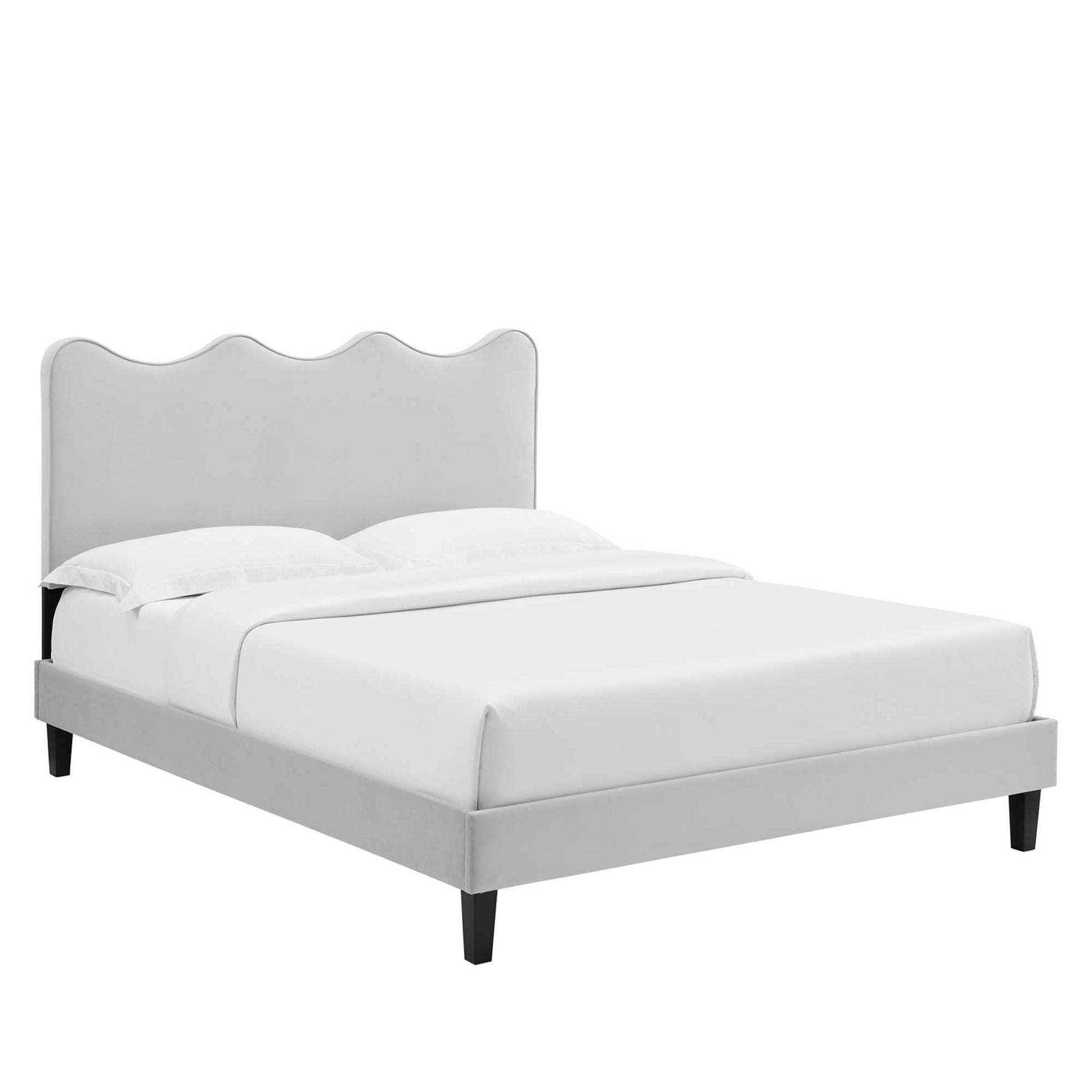 Light gray upholstered platform bed with a scalloped curved headboard and dark tapered legs, dressed in white bedding.