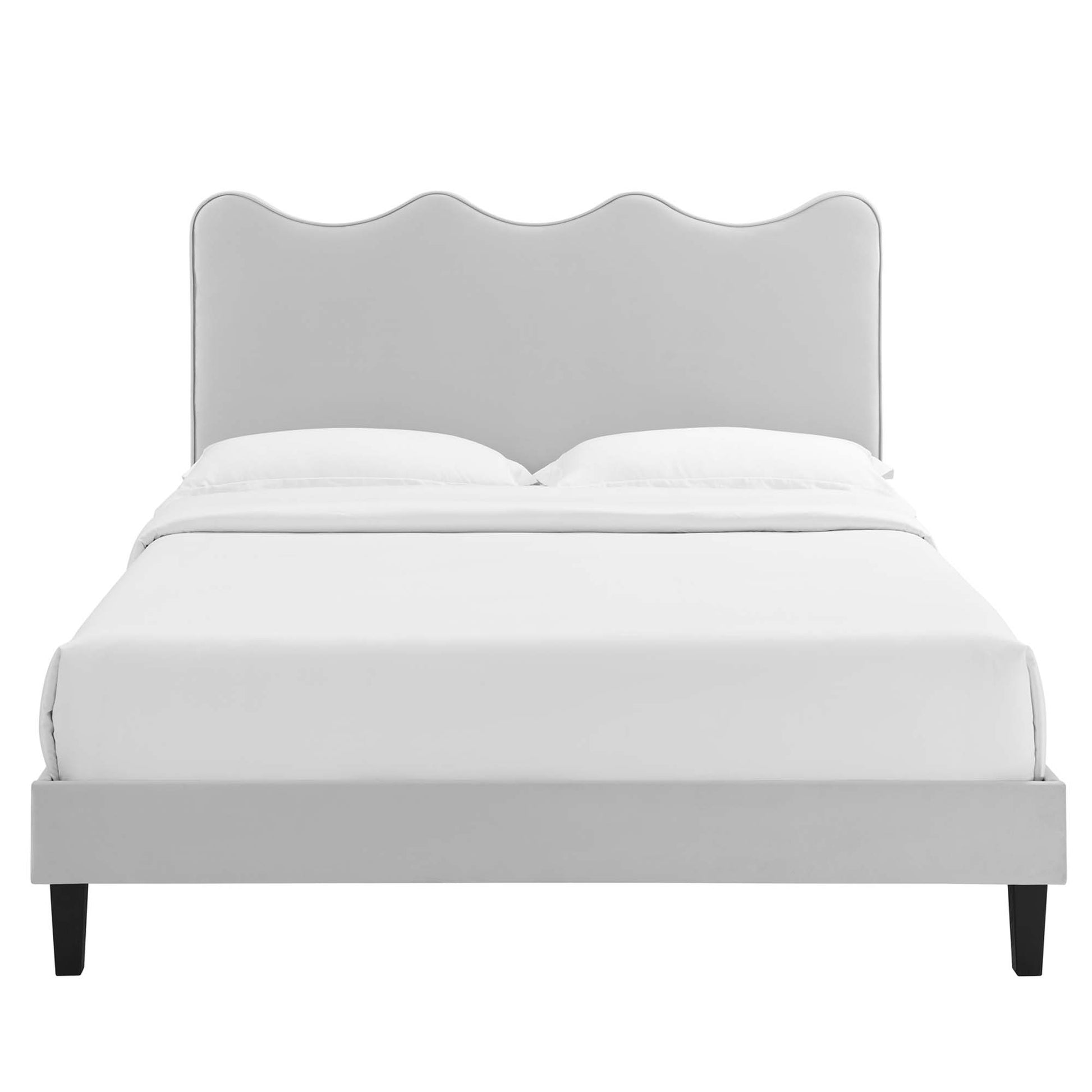Gray upholstered bed with scalloped curved headboard, white bedding, and black tapered legs.