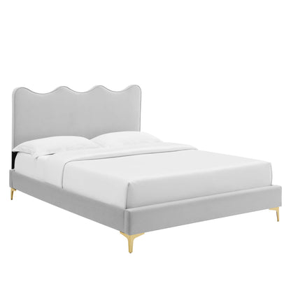 Gray upholstered platform bed with a scalloped wave headboard, white bedding, and gold-tone legs.