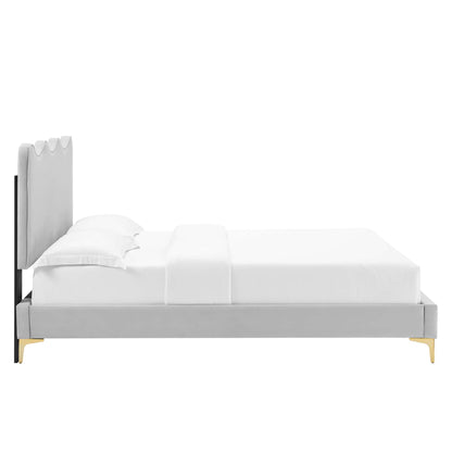 Light gray upholstered platform bed with tall panel headboard, black frame accents and gold legs, white bedding.