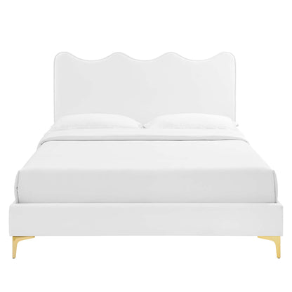 White upholstered platform bed with a scalloped wave headboard, white bedding, and gold-tone legs.