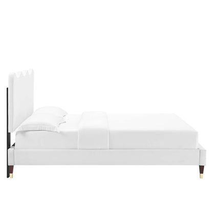 White upholstered platform bed with scalloped headboard, black accents and gold-tipped legs.