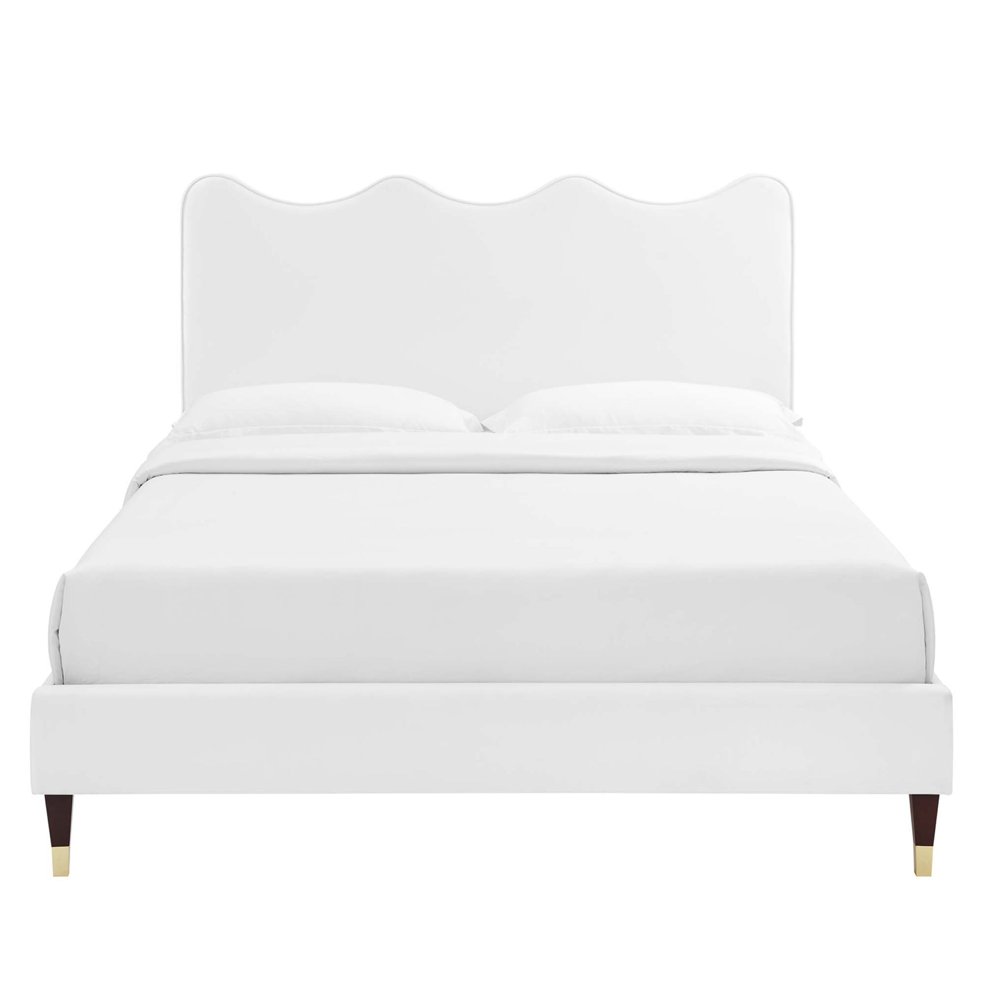 White upholstered bed with a scalloped arched headboard, low footboard, and tapered legs with brass caps.