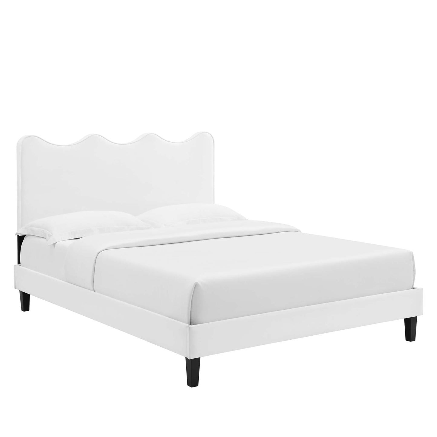 White upholstered platform bed with scalloped curved headboard, white bedding & black tapered legs.