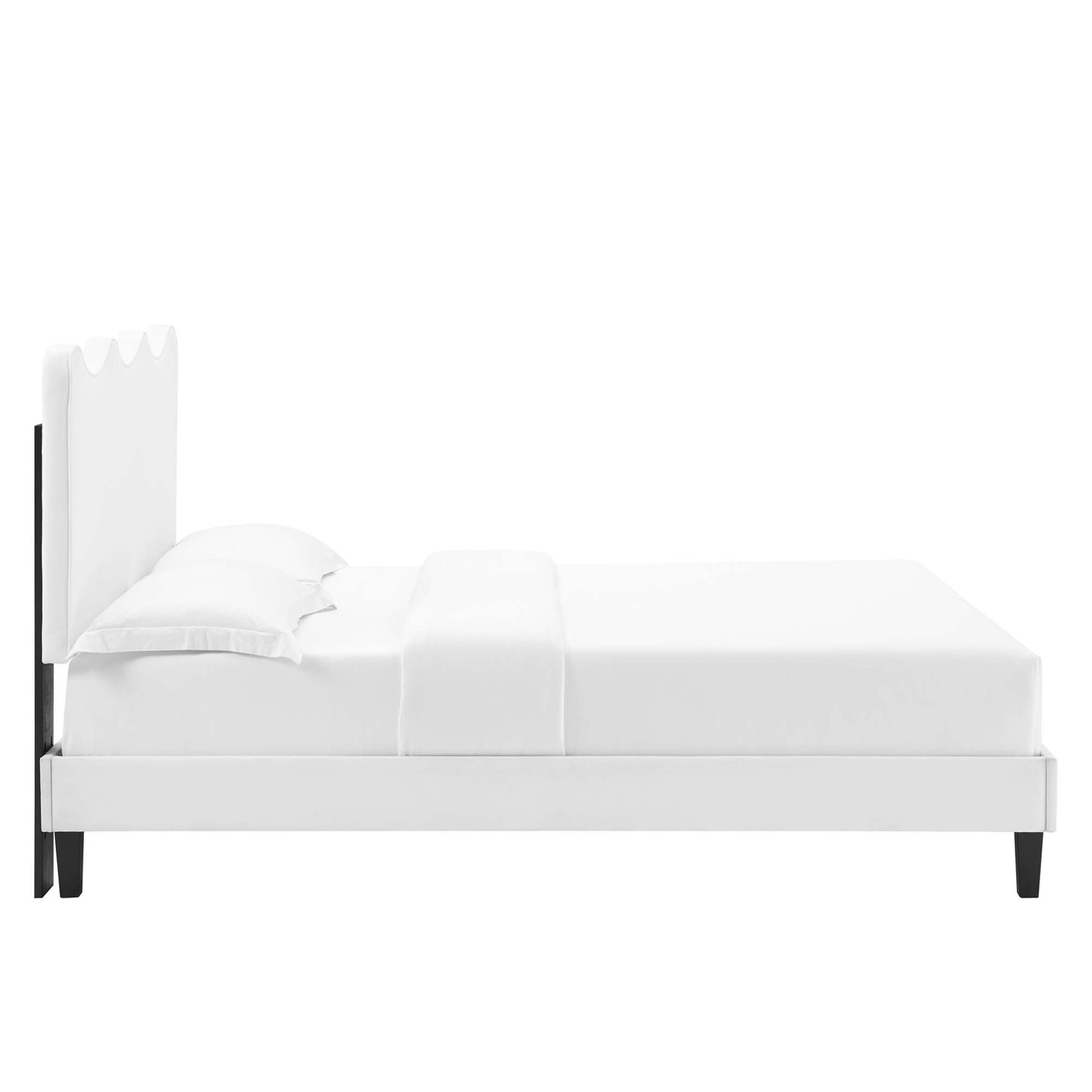 White full platform bed with velvet upholstered headboard, white linens, and dark legs.