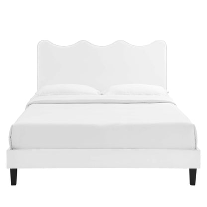 White upholstered bed with a scalloped headboard, platform frame and dark tapered legs; modern, minimal bedroom style.