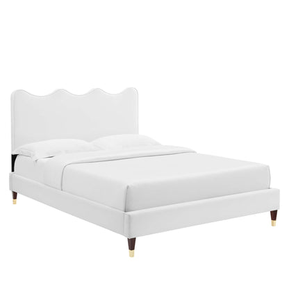 White upholstered queen platform bed with curved scalloped headboard, clean lines, wooden legs with gold caps, white bedding.