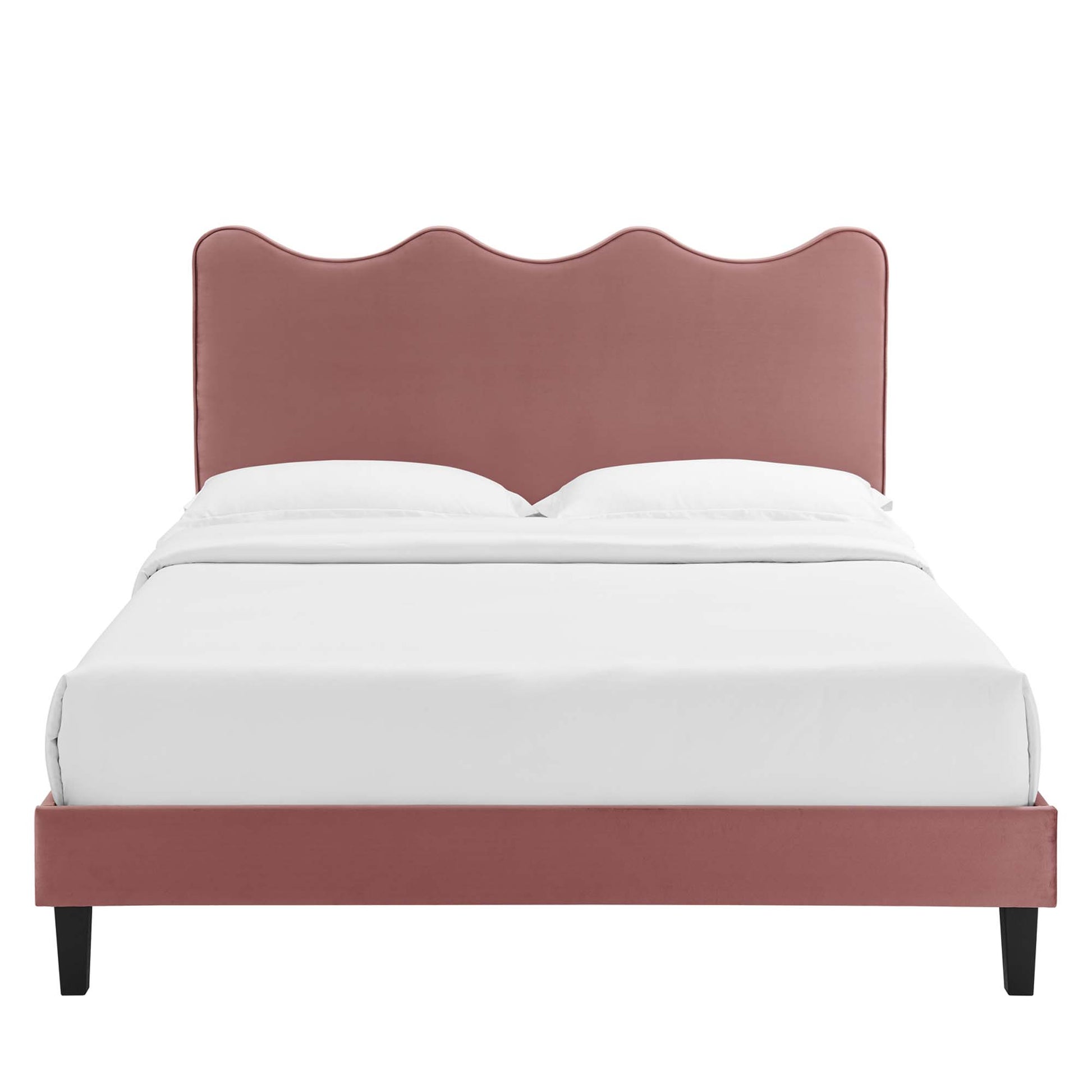 Dusty-rose upholstered bed with scalloped wave headboard, low platform frame, black tapered legs, and white bedding.
