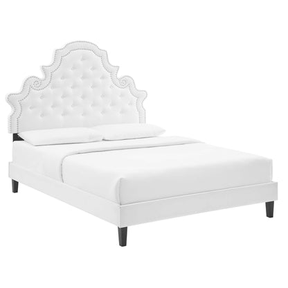 White upholstered bed with tufted, scalloped headboard & nailhead trim, platform frame & dark tapered legs.