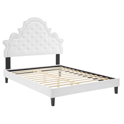 White upholstered queen platform bed with tufted, scalloped headboard and slatted base.