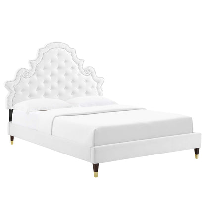 White upholstered platform bed with a scalloped, tufted headboard, nailhead trim, and gold-tipped legs.