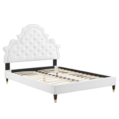 White tufted upholstered full platform bed with an ornate arched headboard, black rails, slat base, and gold-tipped legs