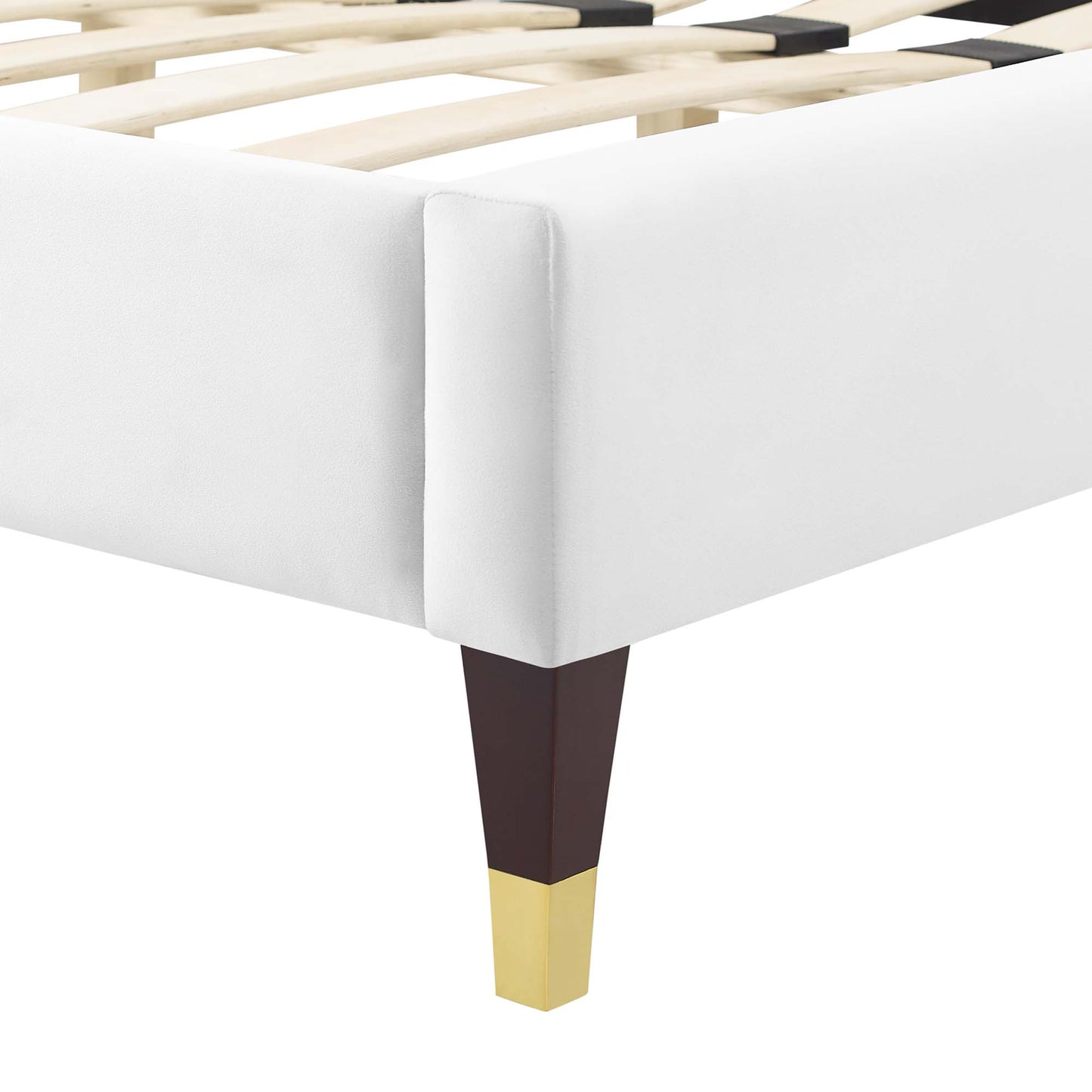 White upholstered platform bed with wooden slats and dark brown tapered leg with a gold tip.