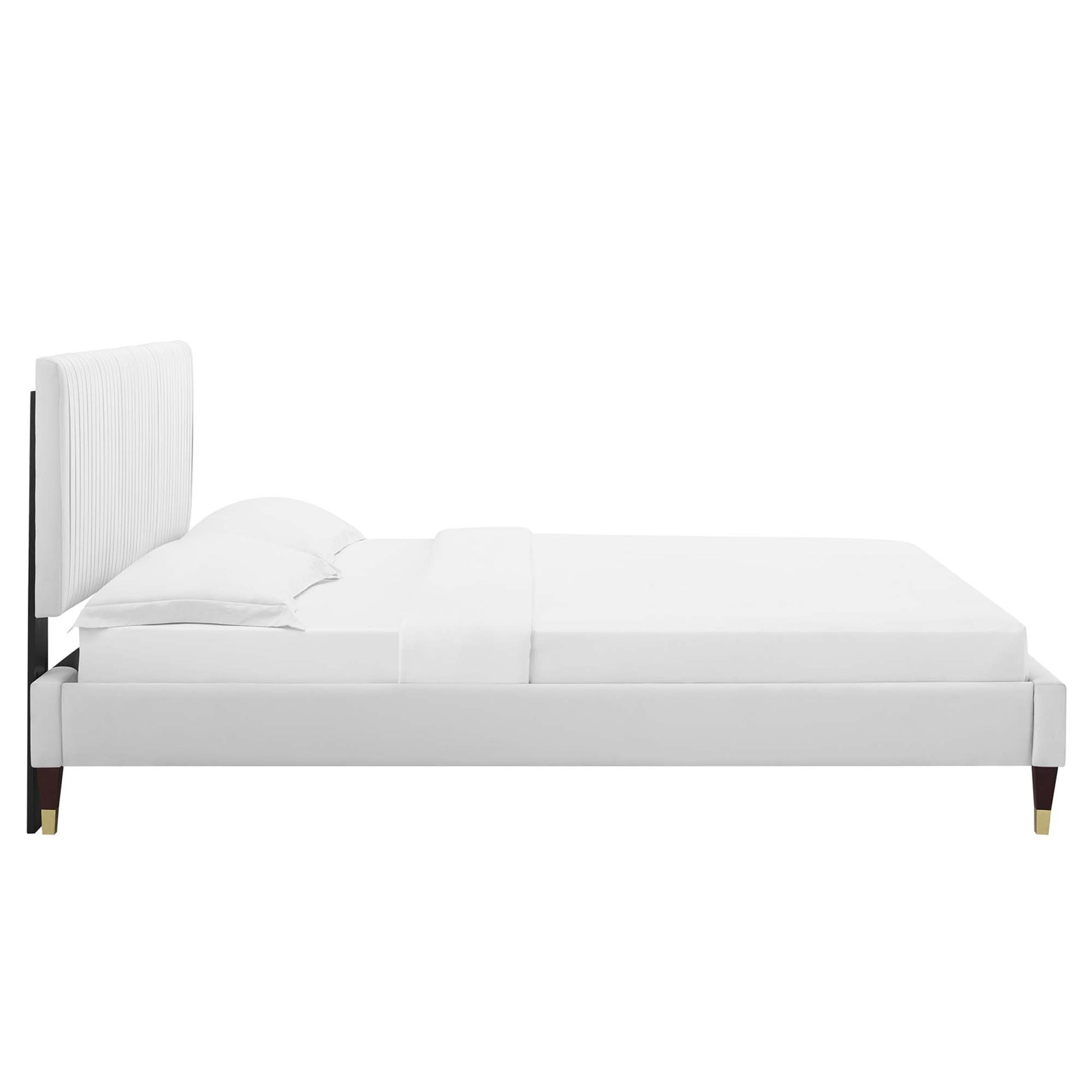 White velvet upholstered full platform bed with a tall padded headboard, white linens and gold-tipped legs.