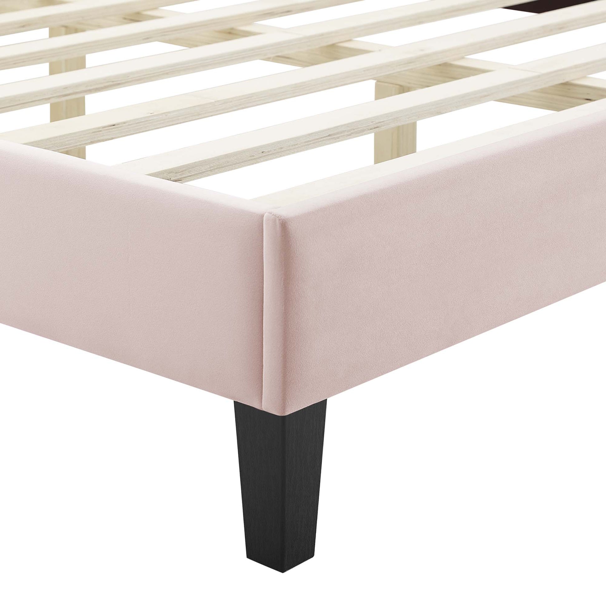 Pink upholstered bed frame with slatted wooden base & black tapered leg.