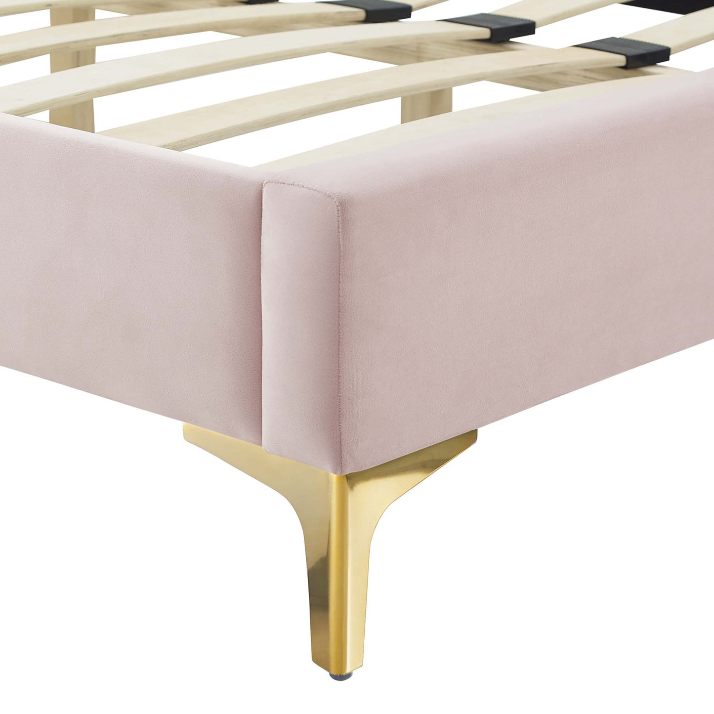 Corner view of red velvet upholstered full platform bed with gold metal legs and a slatted wooden base.