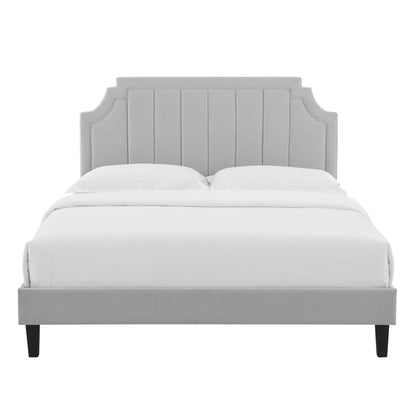 Gray upholstered bed with tall paneled headboard featuring curved top corners, white bedding, dark tapered legs.