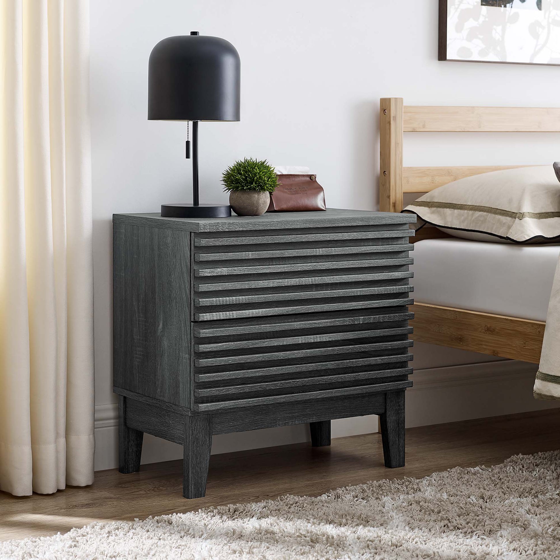 Charcoal gray two-drawer nightstand with a black dome lamp and a small plant beside a wood bed in a modern rustic bedroom.