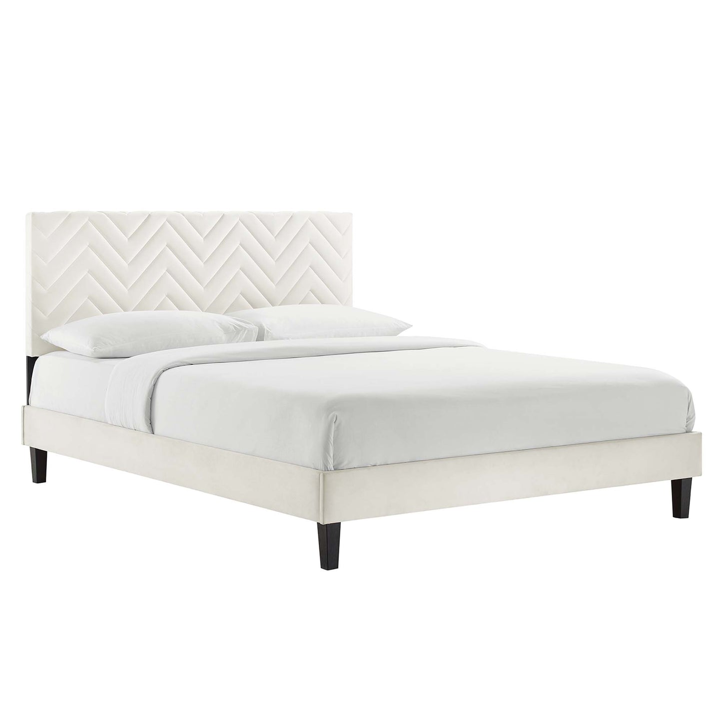 White upholstered twin platform bed with chevron tufted headboard, low platform frame, dark wood legs, white bedding.