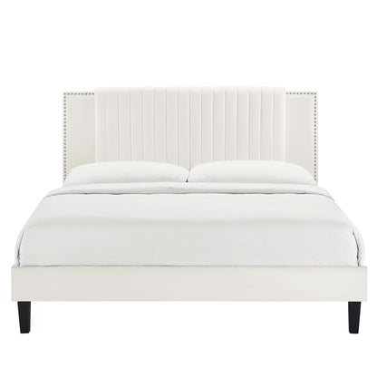 White upholstered platform bed with tall vertical-channel headboard, nailhead trim, dark legs, dressed in white bedding.