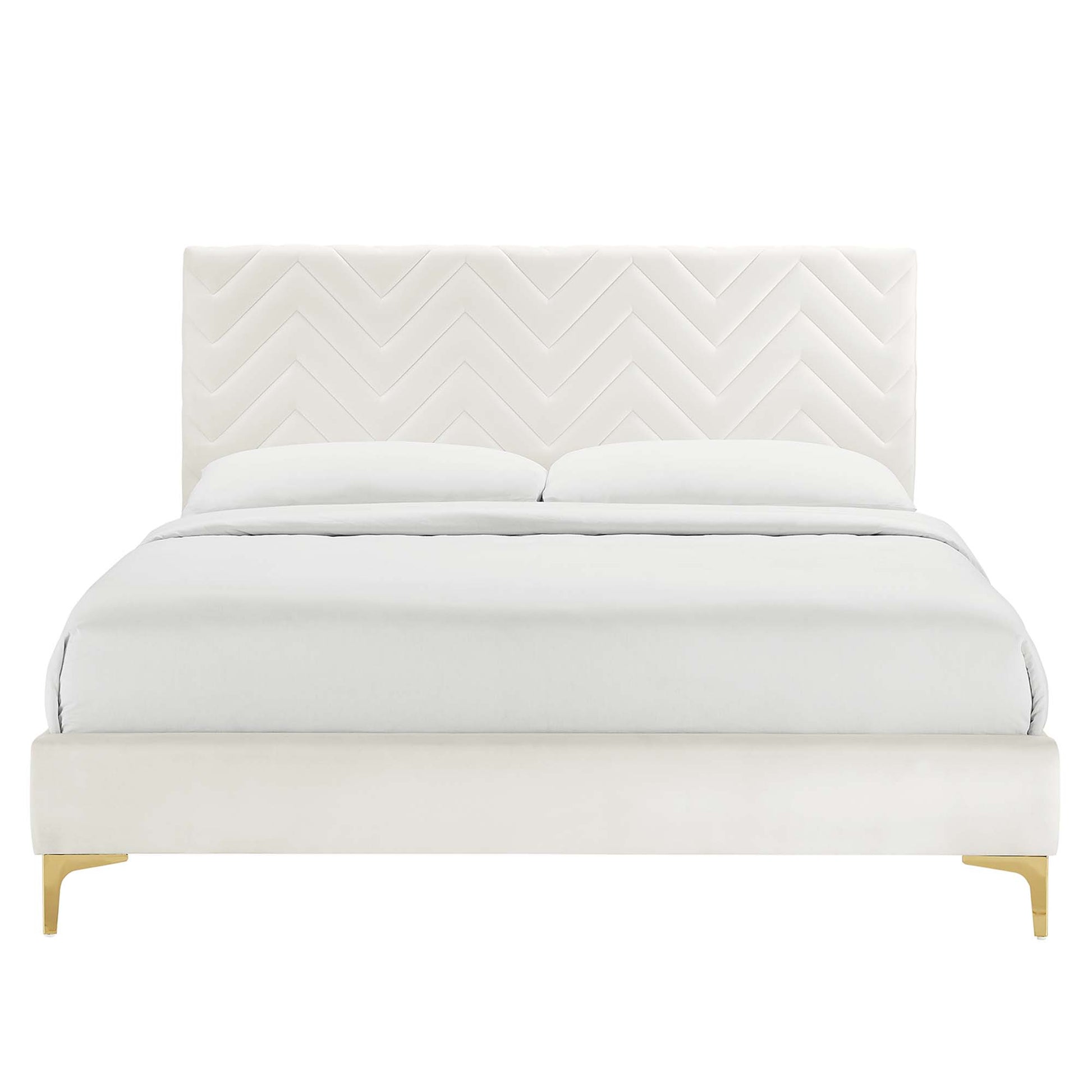 White upholstered full platform bed with chevron-tufted headboard, white bedding, and white platform with wooden legs.