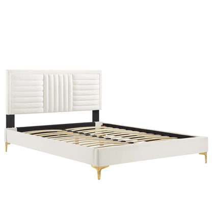 White upholstered platform bed with tall tufted headboard, black side rails, wood slat base and gold legs.