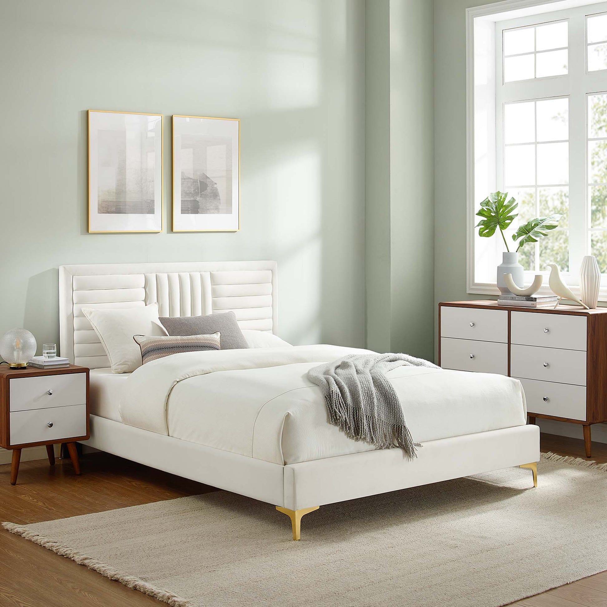 White upholstered platform bed with tufted headboard, gray throw, mid-century nightstands, wooden dresser, pale green walls