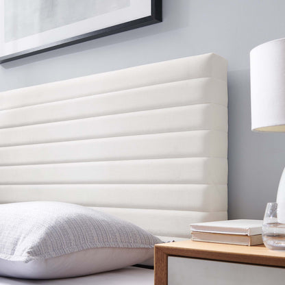 White upholstered headboard with horizontal channel tufting, shown with white bedding and a wooden nightstand.