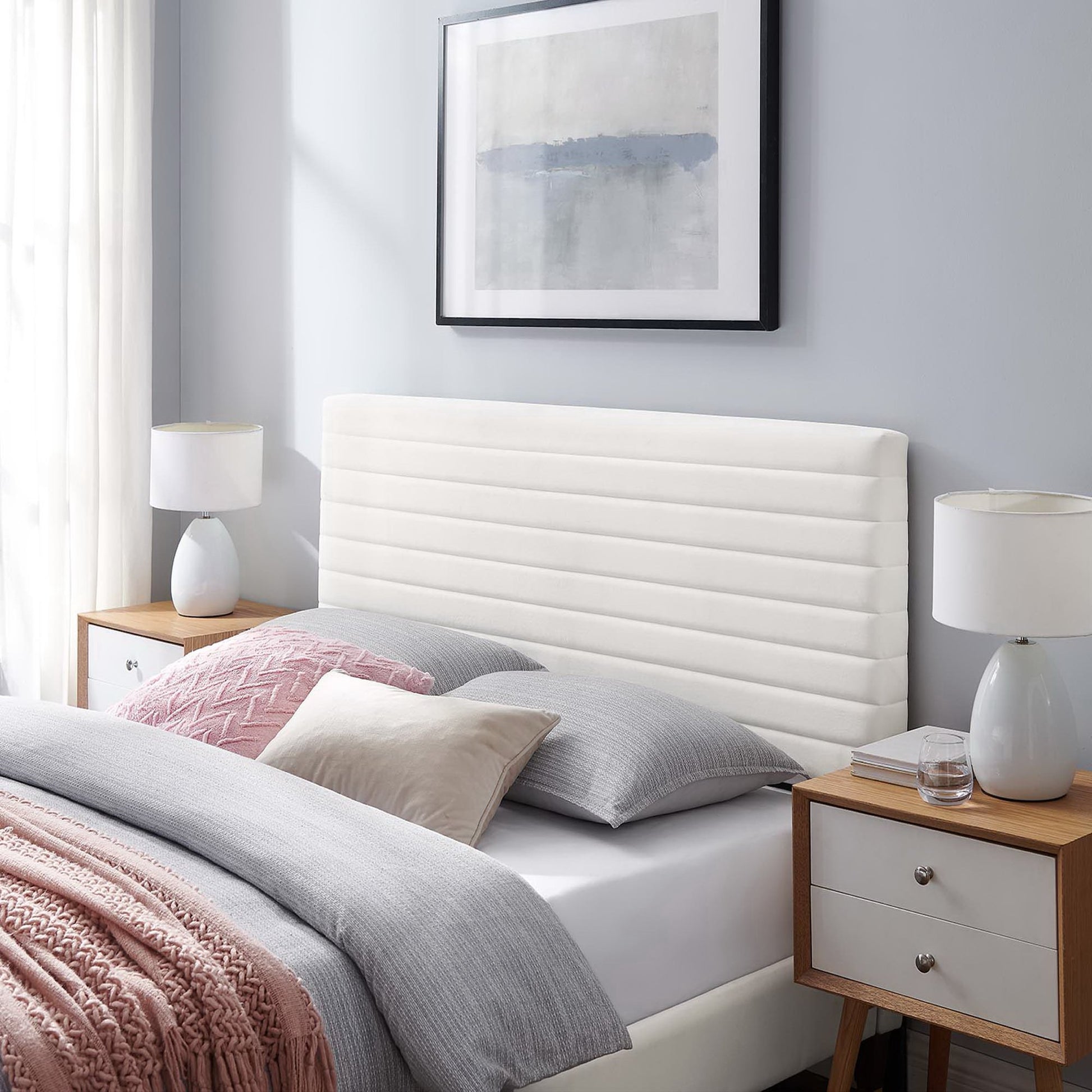 White upholstered headboard with gray bedding in a bedroom scene.