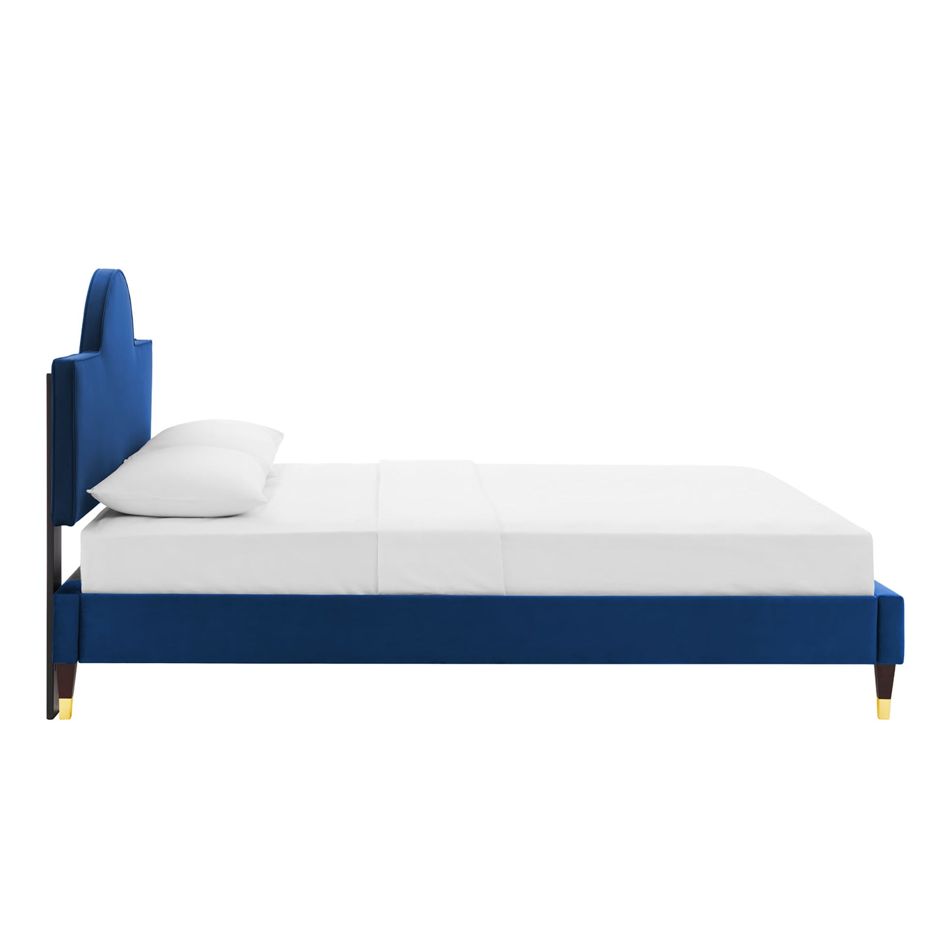 Navy blue upholstered platform bed with tall cushioned headboard, dark wood legs with gold caps, white bedding.