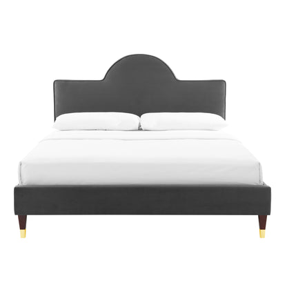 Charcoal gray upholstered bed with arched headboard, low platform frame, wooden tapered legs with gold tips.