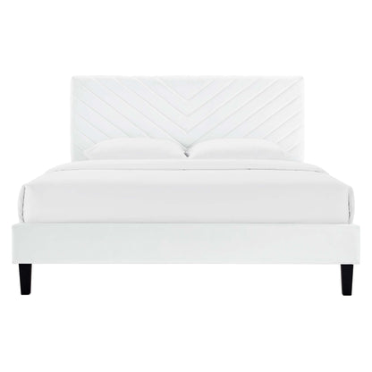 White upholstered full platform bed with chevron-patterned headboard, white bedding, and black tapered legs.