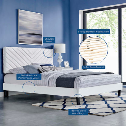 White platform bed with tufted chevron-detail headboard, stain-resistant velvet, tapered black wood legs, grey bedding.