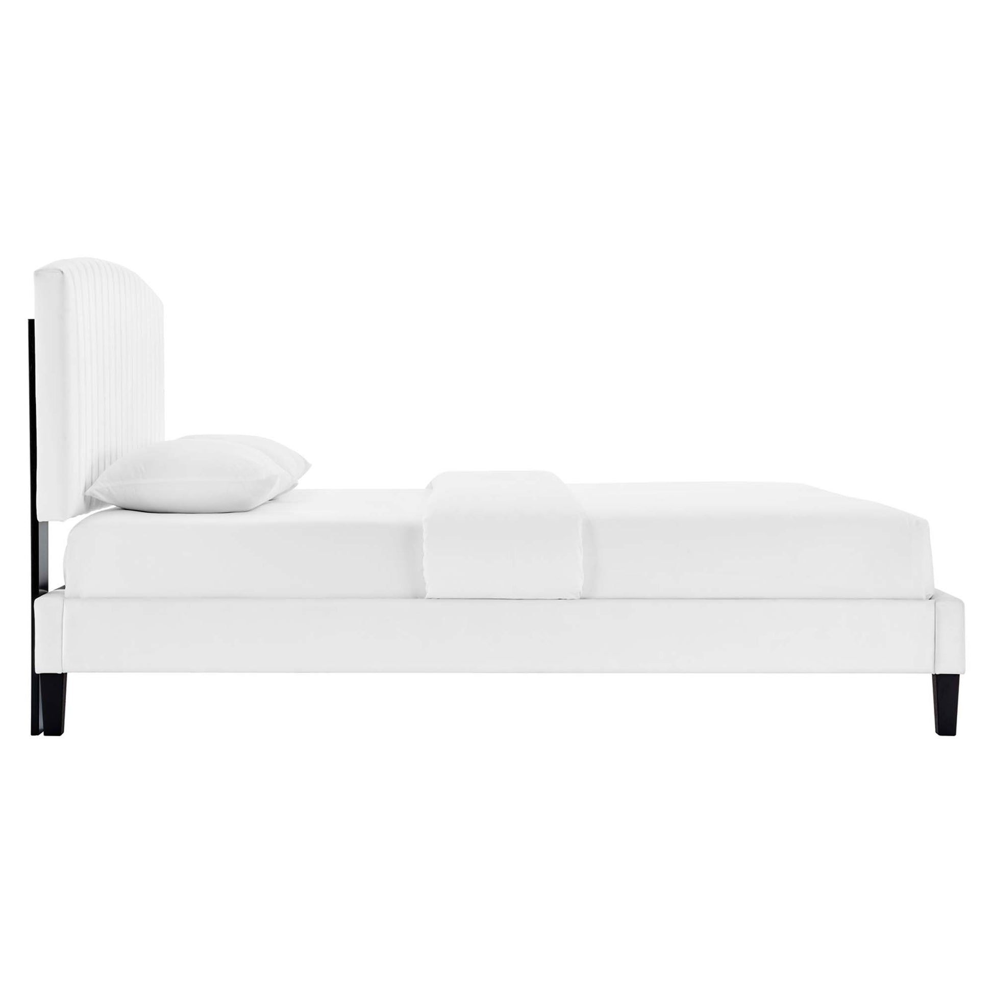 White upholstered platform bed with tall padded headboard, black legs, and white bedding.