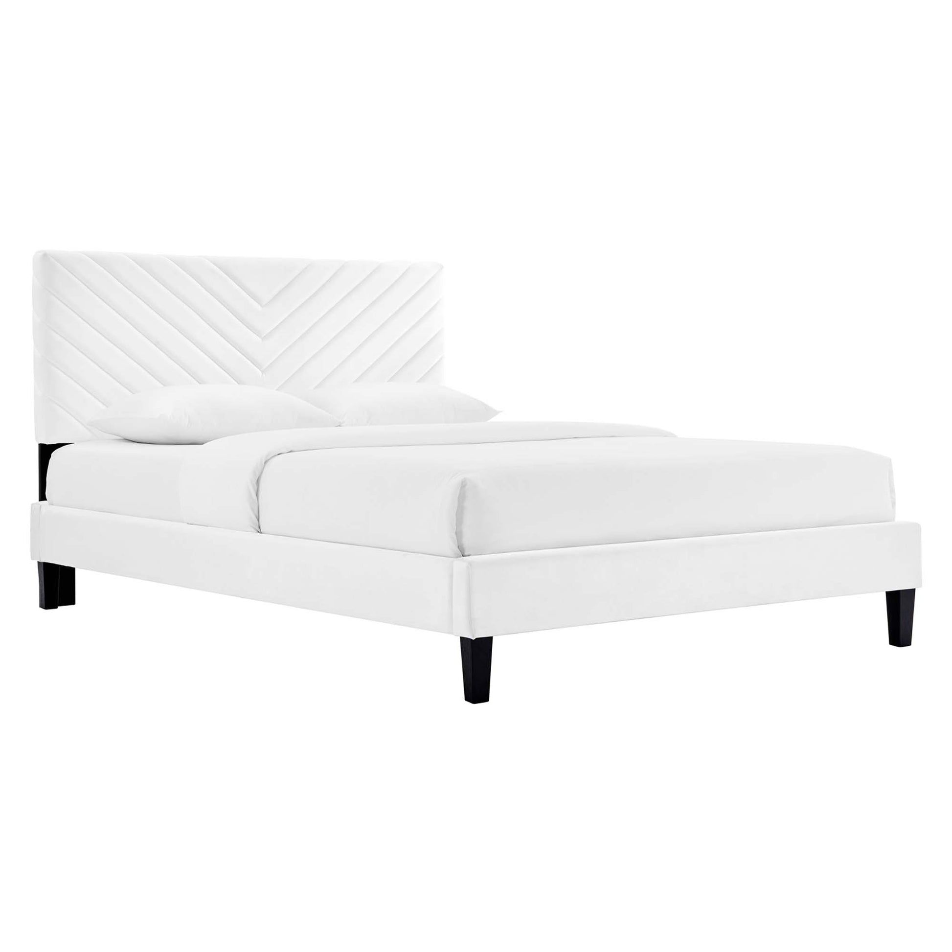 White upholstered platform bed with chevron quilted headboard, white bedding, and black tapered legs.